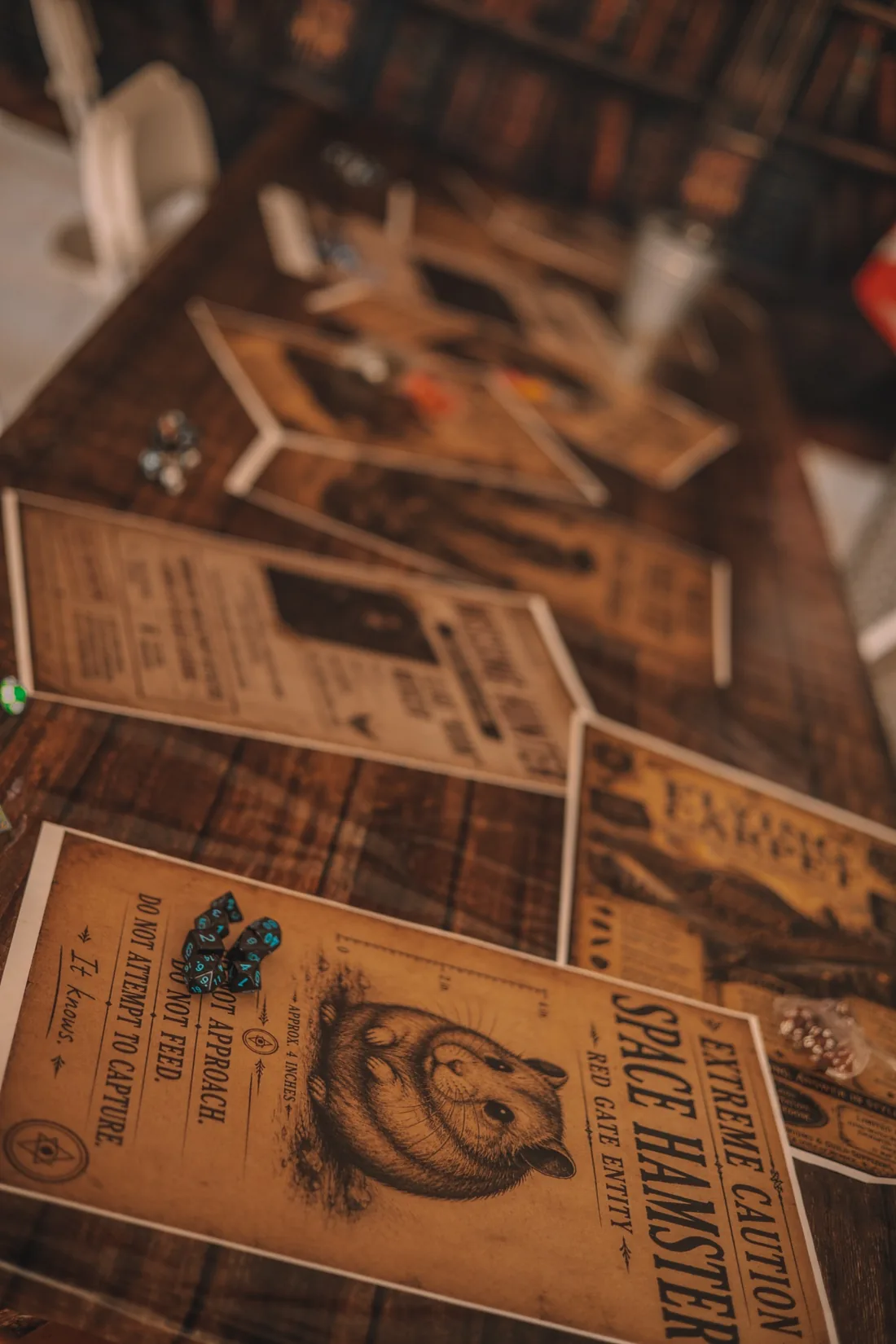 Dice resting on illustrated Gatefall creature posters, including a Space Hamster warning.