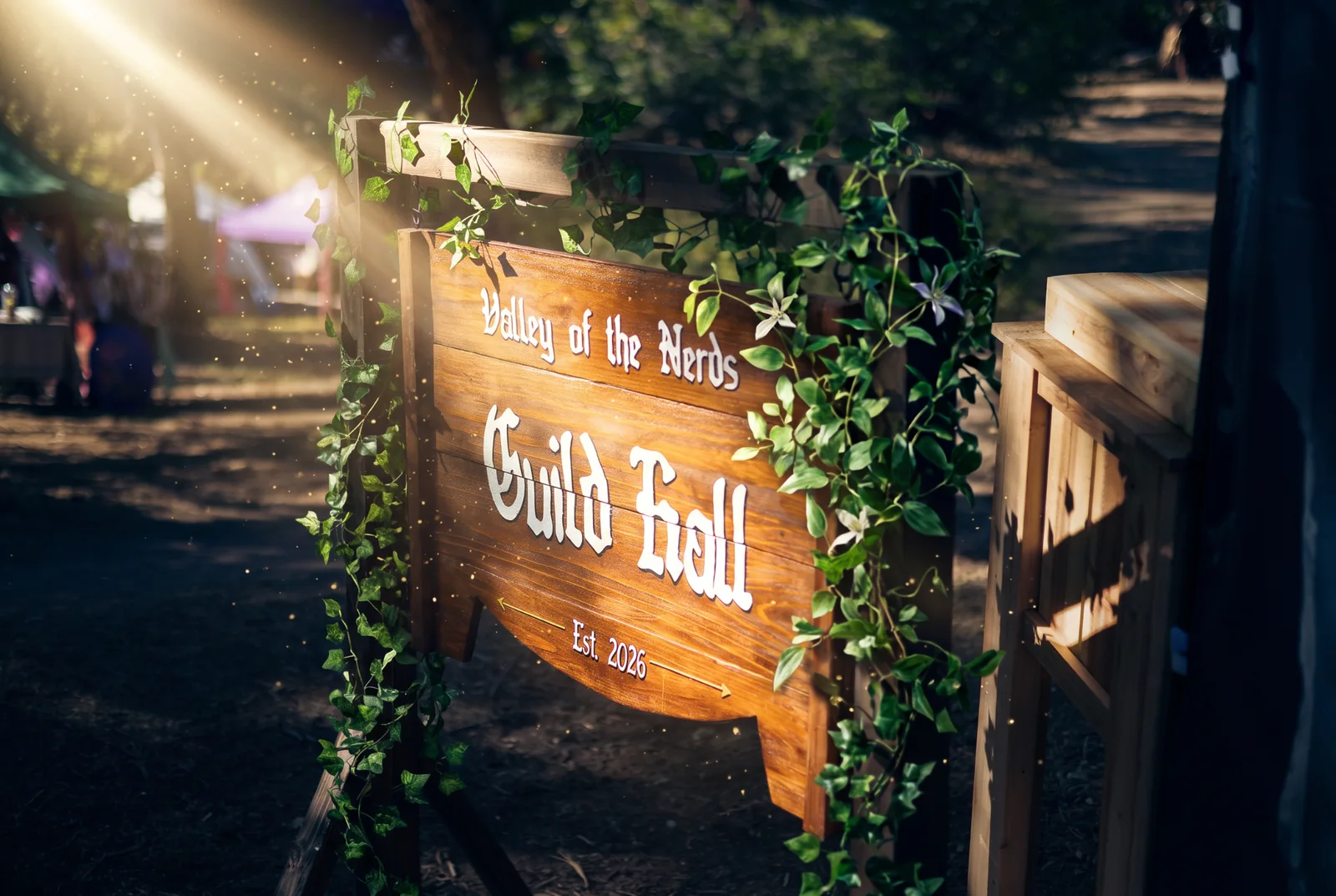 The Valley of the Nerds wooden Guild Hall sign, wrapped in ivy and illuminated by a warm sunbeam at an outdoor event